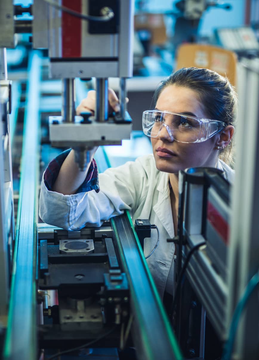 An engineer examining machine part on a production line