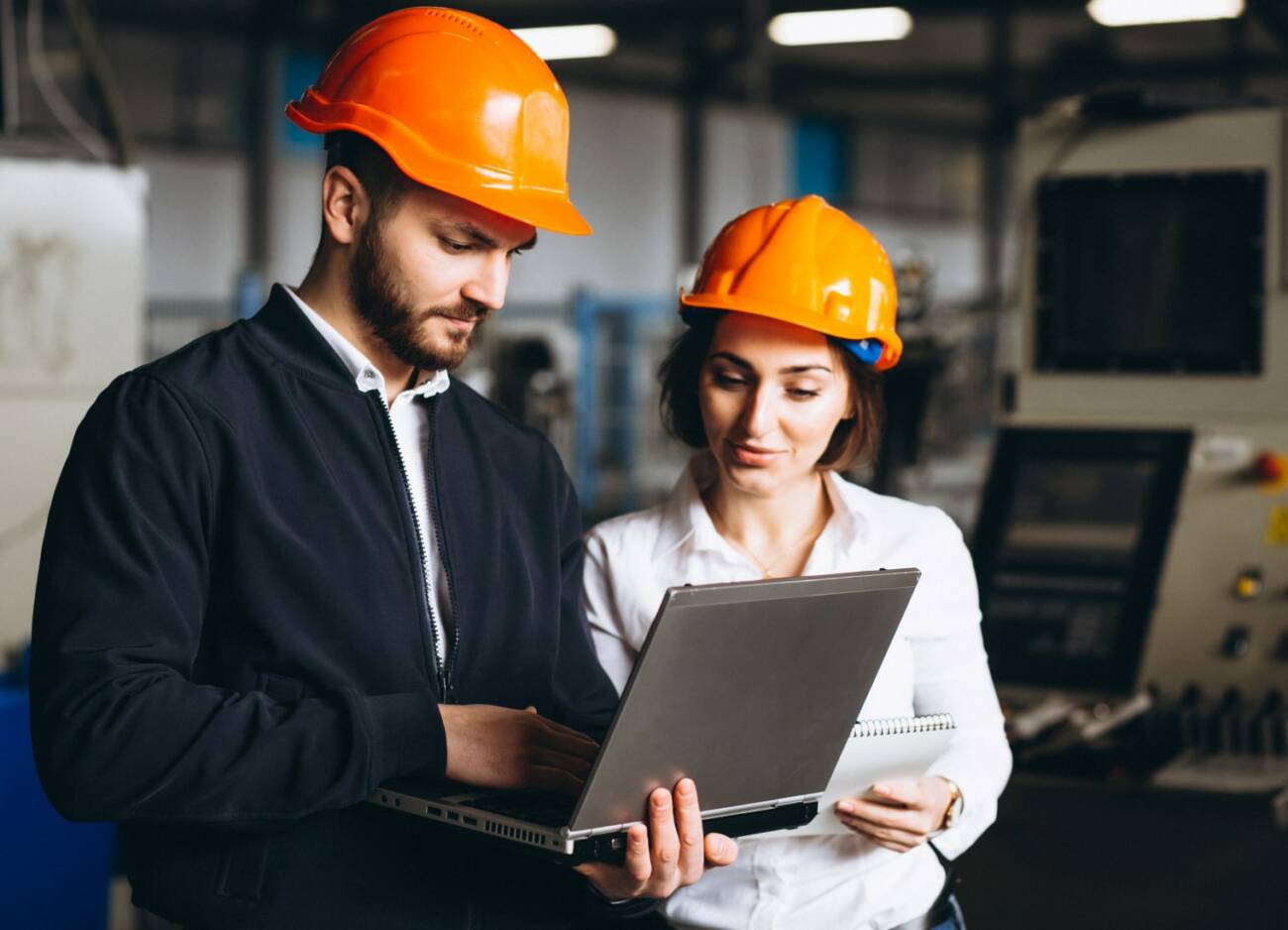 two industrial workers examining a laptop in a factory environment